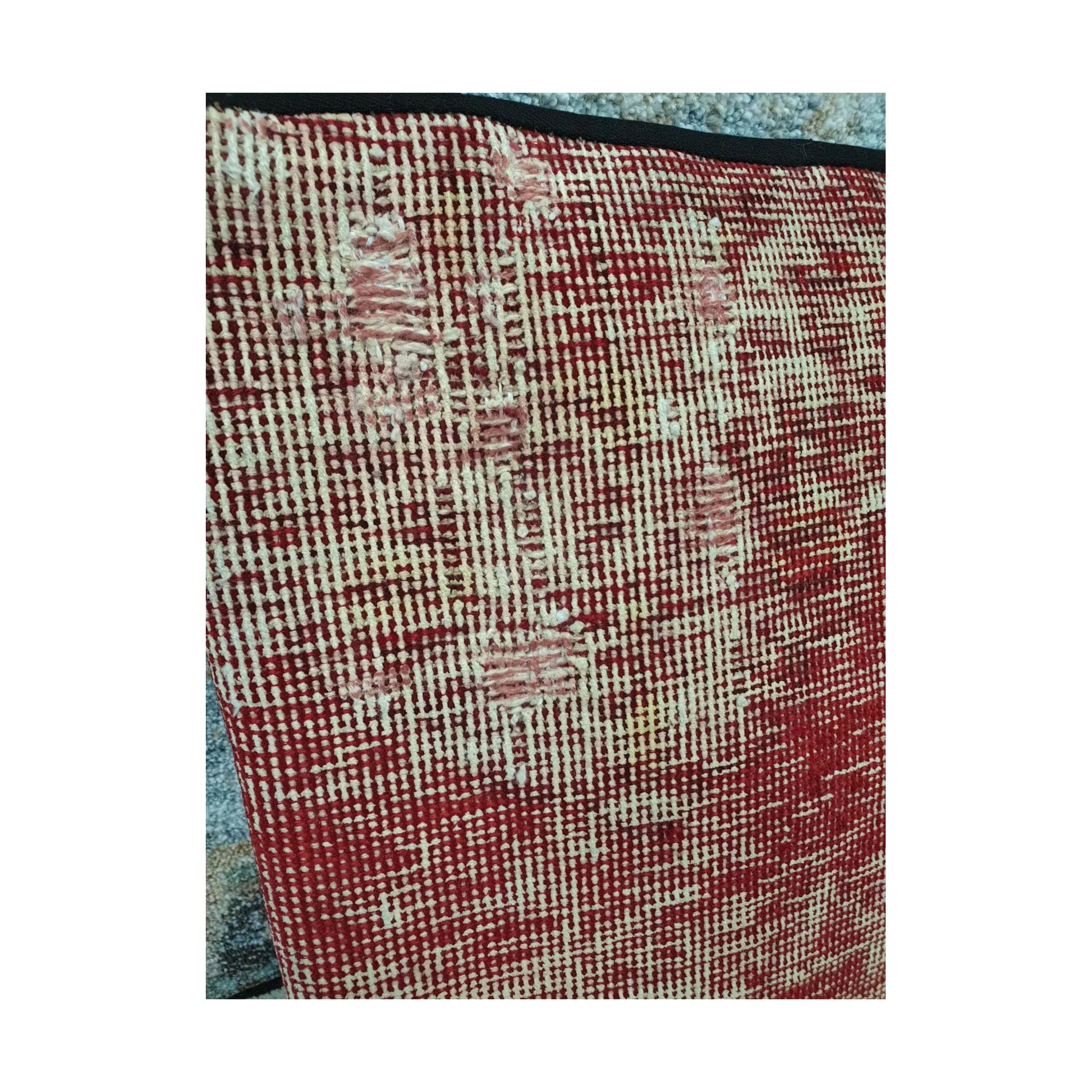 Close view of ivory linear traces and soft blush accents across the muted-red wool surface