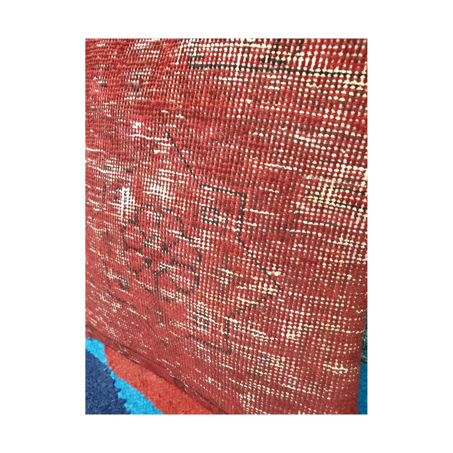Detailed angled view of the faded central medallion and linear pattern on the red Persian cushion cover