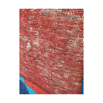 Detailed angled view of the faded central medallion and linear pattern on the red Persian cushion cover