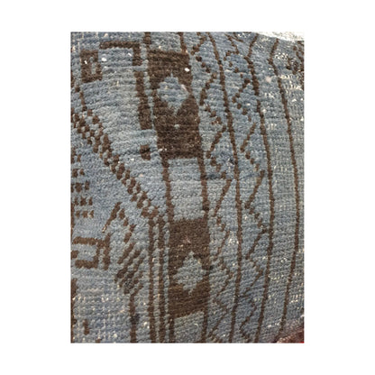 Close-up of dark brown geometric forms and linear border bands across the slate blue wool pile