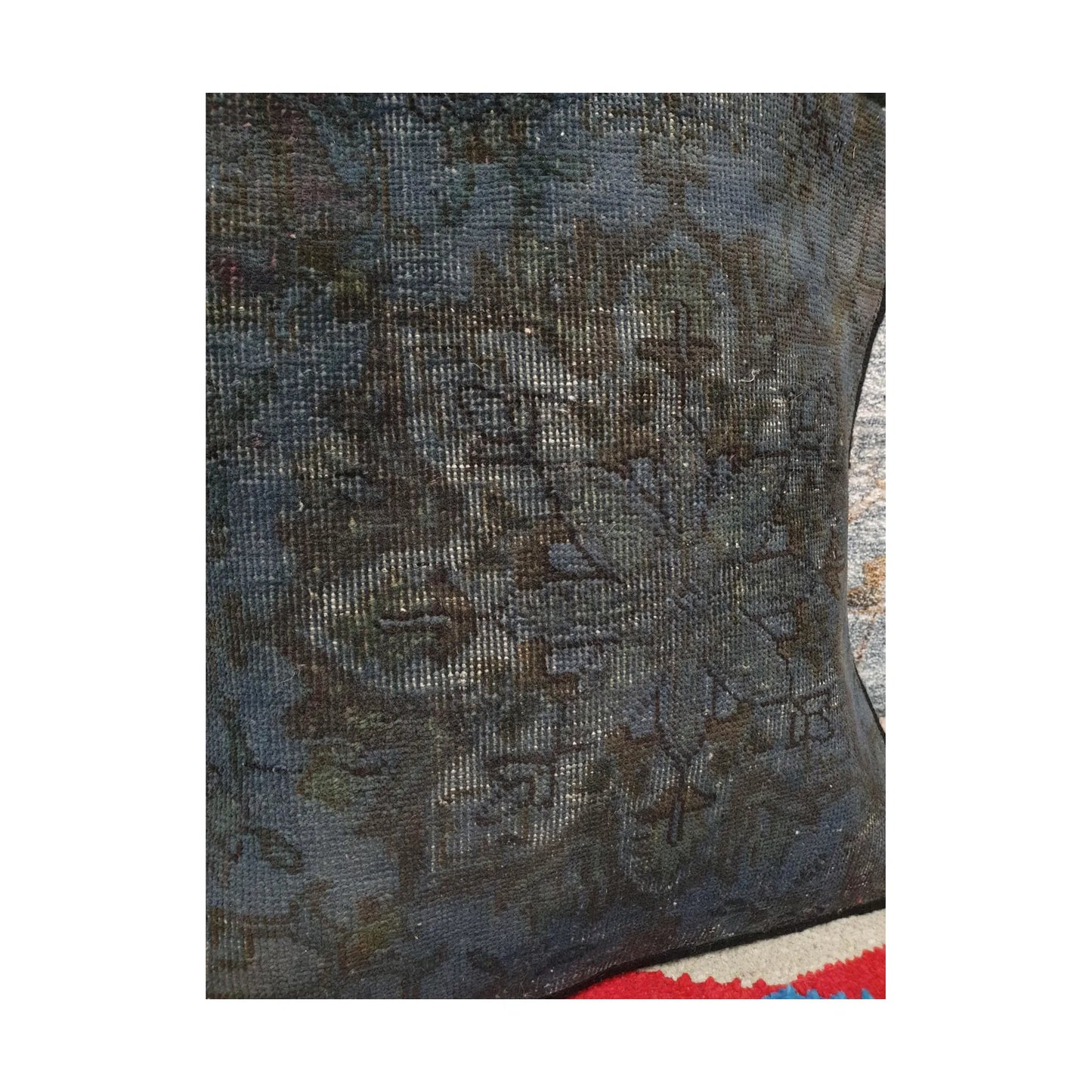 Angled close view of dark brown floral forms across the smoky blue Persian cushion cover