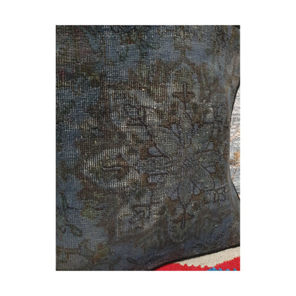 Angled close view of dark brown floral forms across the smoky blue Persian cushion cover