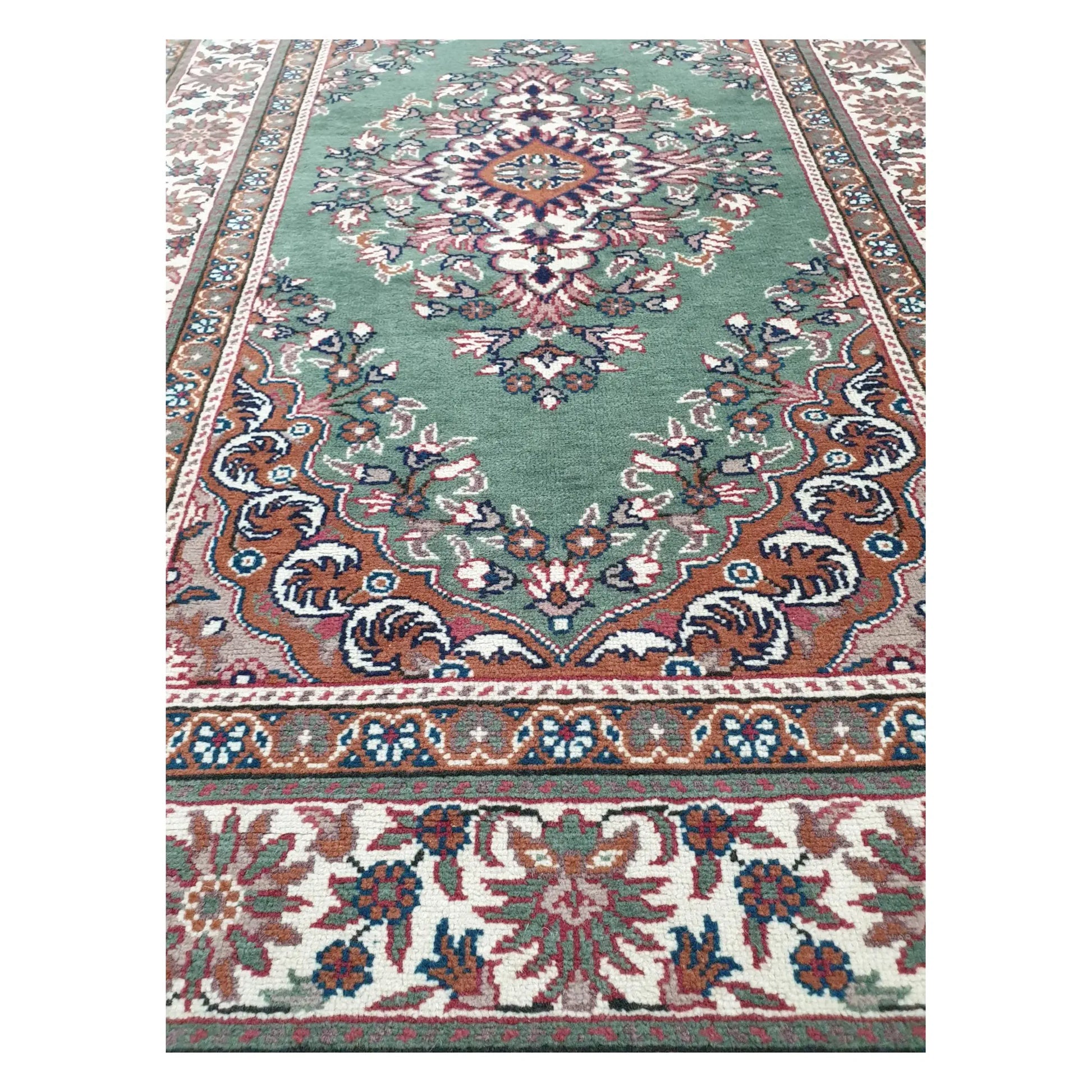 Lower field detail of a vintage Persian Tabriz rug with sage green ground and ornate floral border