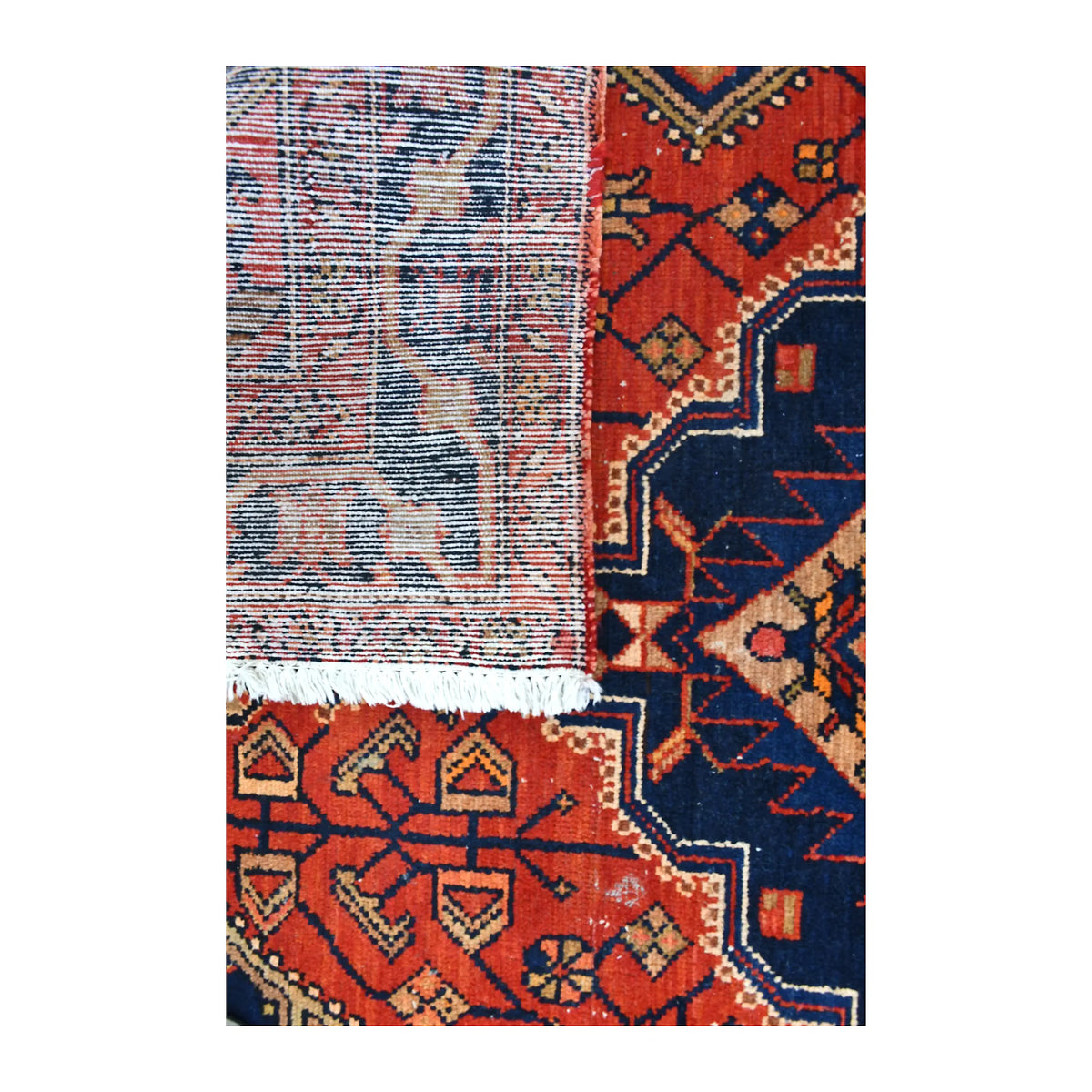 Folded-corner detail of Persian Zanjan rug showing the reverse weave, geometric front design and pale fringe