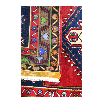 Folded-corner detail of vintage Yahyali rug showing the reverse weave beside its red and navy front and white fringe